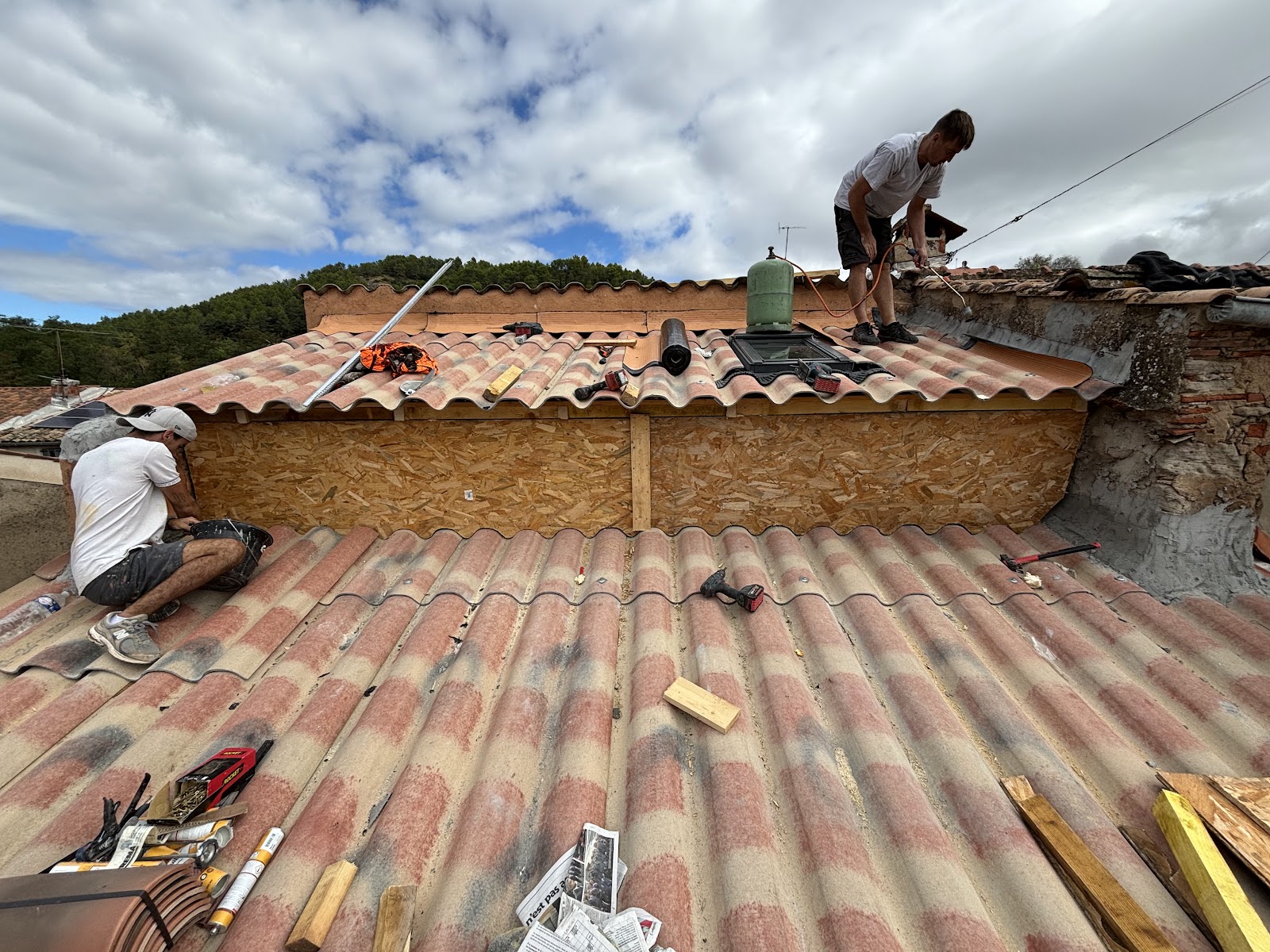 Deux couvreurs sur un toit en rénovation avec fenêtre de toit installée